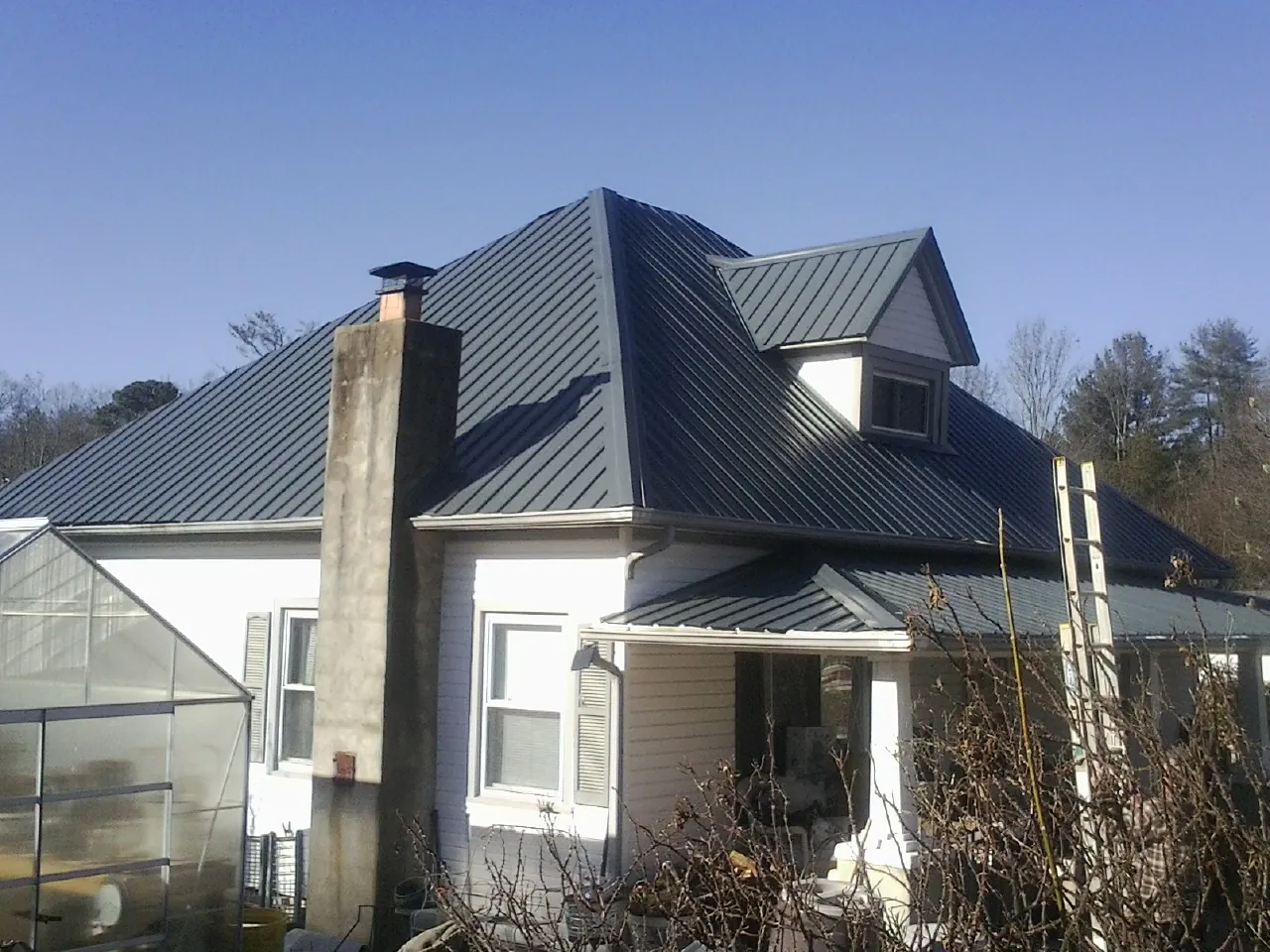 Dark blue standing seam metal roof on a white farmhouse with dormer — Slate & Tile Roof Repair by Roofing Brothers in Cub Run