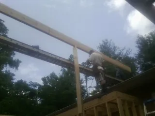Carpenter setting a ridge beam over a new addition frame — Ice Dam Removal by Roofing Brothers in Cub Run