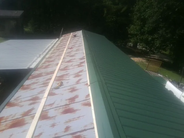 Old rusted panels beside newly installed green metal roofing — Wind Damage Roof Repair by Roofing Brothers in Cub Run