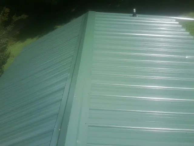 New green metal panels meeting at the ridge of a roof — Flat Roof Repair work by our crew in Cub Run