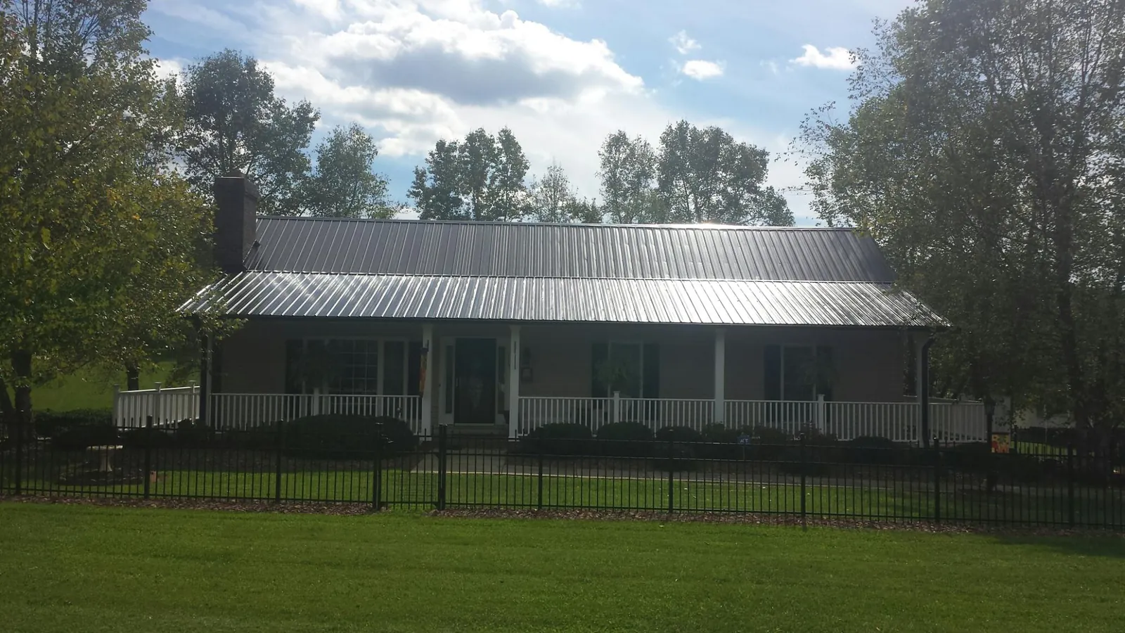 Gray metal roof on a brick ranch with a full width front porch — Gutter Guard Installation work by our crew in Cub Run