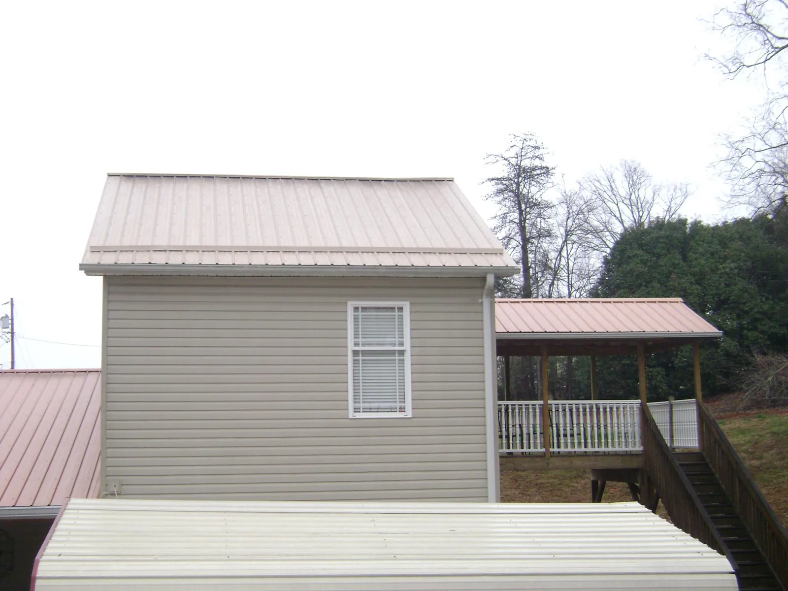 Tan metal roofs on a two story addition and attached porch, from a Roof Replacement job in Cub Run
