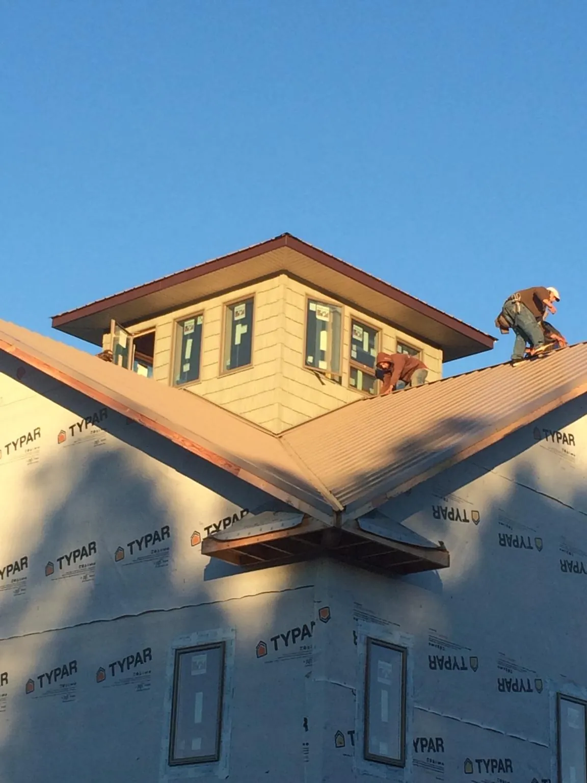 Roofers working around a rooftop cupola on a new metal roof at sunset — Roof Waterproofing in Cub Run by Roofing Brothers